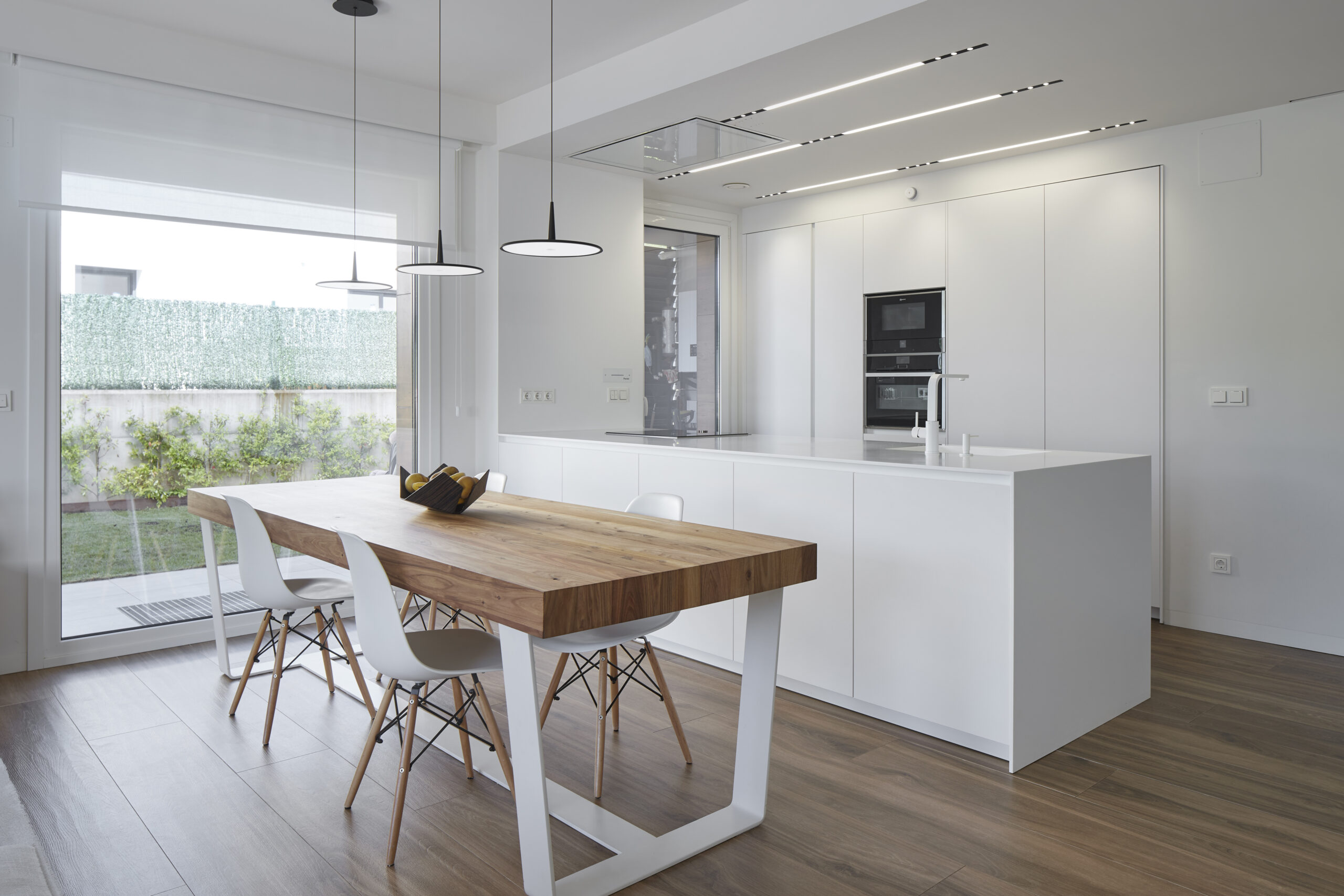 Cocina blanca con isla de madera y falso techo de pladur con focos lineales