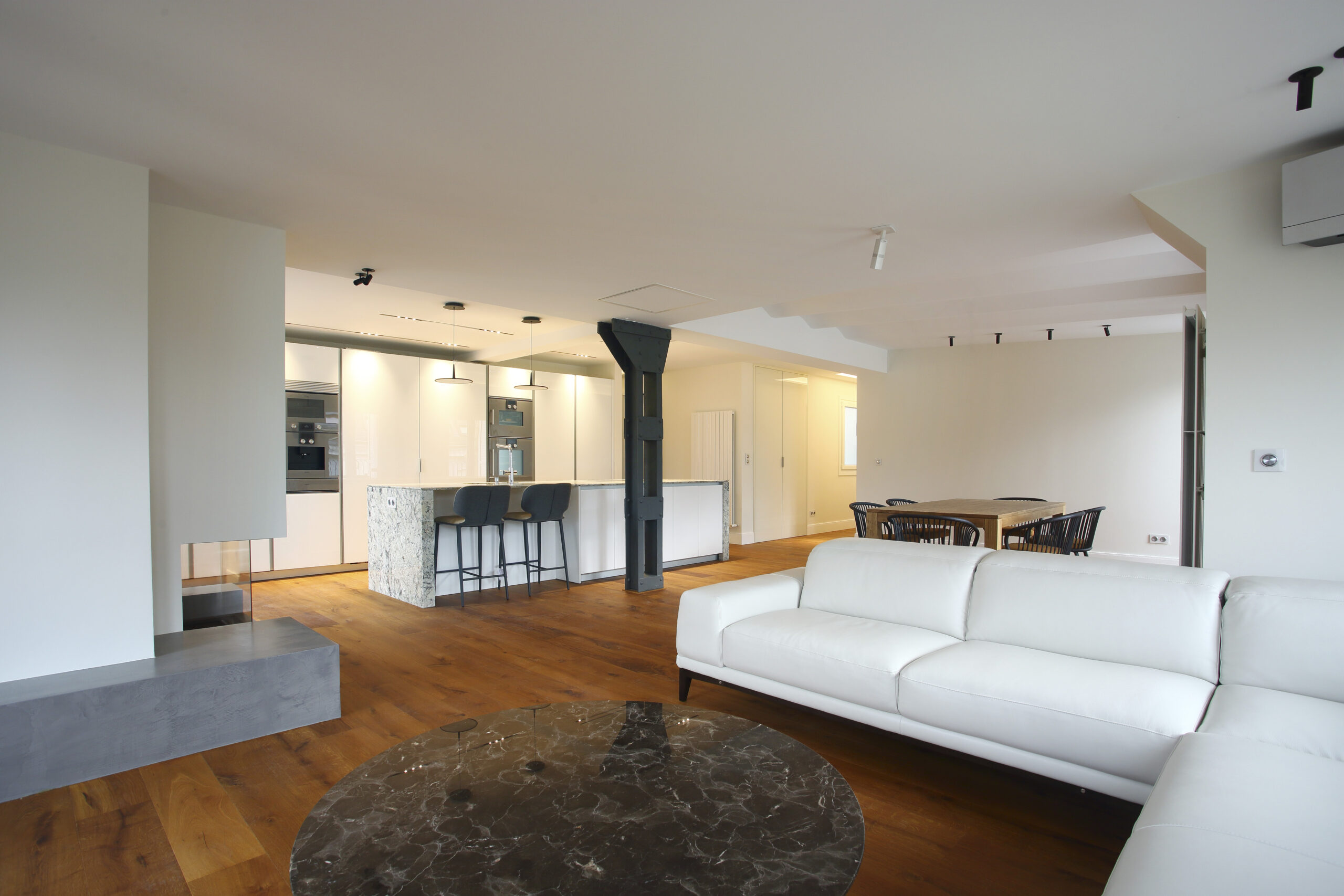 Salón abierto con cocina y sofá blanco, reforma integral en San Sebastián